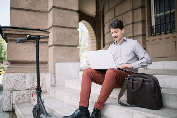 Empresario con laptop trabajando fuera del edificio
 - Foto, imagen