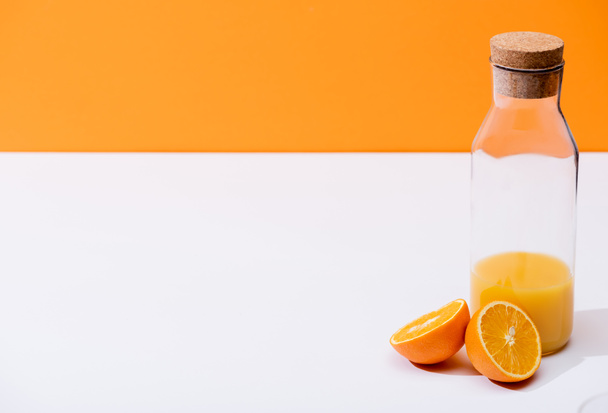 Taze portakal suyu şişede, olgun portakal yarımları beyaz yüzeyde, portakalda izole edilmiş. - Fotoğraf, Görsel