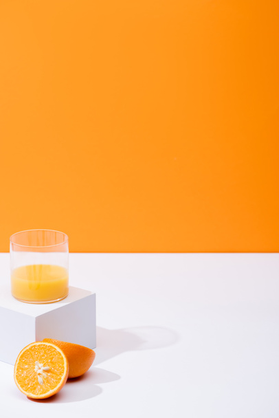 zumo de naranja fresco en vaso cerca de naranjas maduras en superficie blanca aislada en naranja
 - Foto, imagen
