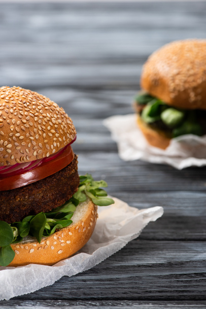 selective focus of tasty vegan burgers with microgreens and radish served on wooden table - 写真・画像