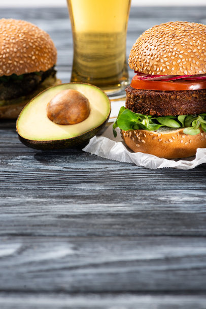 Lezzetli vejetaryen burgerler ahşap masada bira ve avokado ile servis edilir. - Fotoğraf, Görsel