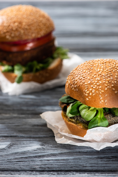 selective focus of tasty vegan burgers with microgreens served on wooden table - Fotoğraf, Görsel