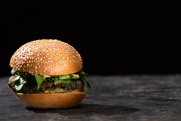 chutný veganský burger s mikrozelení podávaný na texturovaném povrchu izolovaném na černé - Fotografie, Obrázek