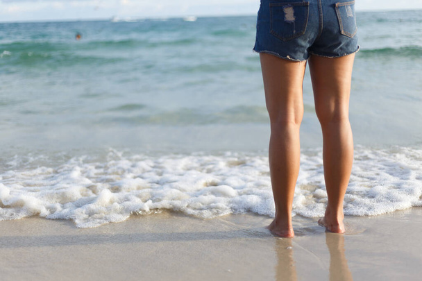 Woman legs standing on white sand beach. - Foto, immagini
