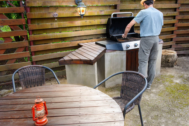  Homem limpeza churrasco em seu jardim traseiro, preparação para fritar carne
 - Foto, Imagem