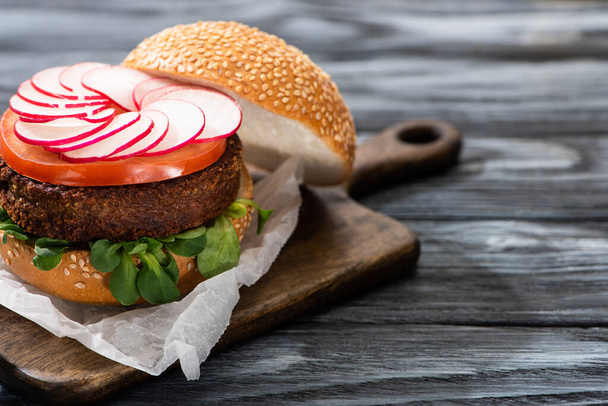 tasty vegan burger served on cutting board on wooden table - Фото, зображення