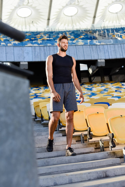 selective focus of young sportsman walking on stairs at stadium - Valokuva, kuva