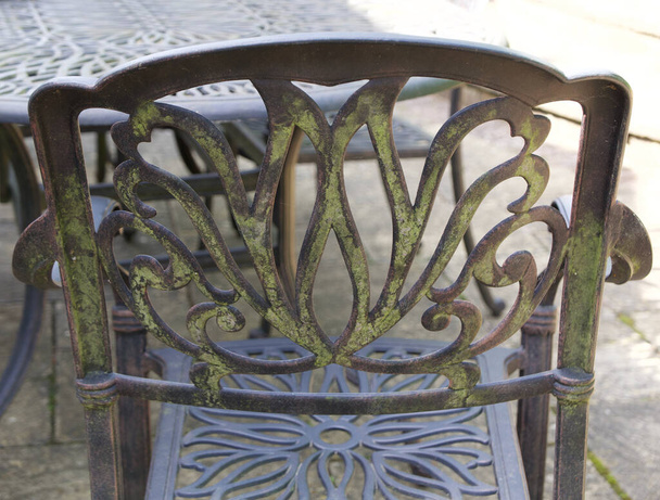 Croissance de moisissure verte sur le dos de la chaise métallique à motifs sur le patio
 - Photo, image