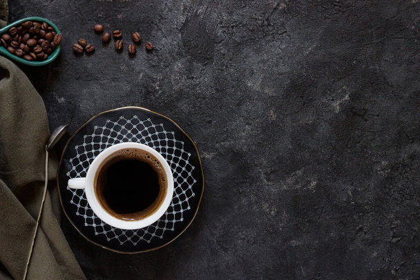 Білий зі свіжою кавою на темній тарілці з кавовими зернами на темному тлі з зеленою тканиною та антикварною кавовою ложкою
 - Фото, зображення