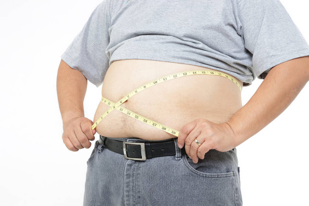 Hombre gordo, vientre muy grande, de pie, usando cinta métrica alrededor de su cintura. Concepto de pérdida de peso, prevención de enfermedades. Fondo blanco
 - Foto, Imagen