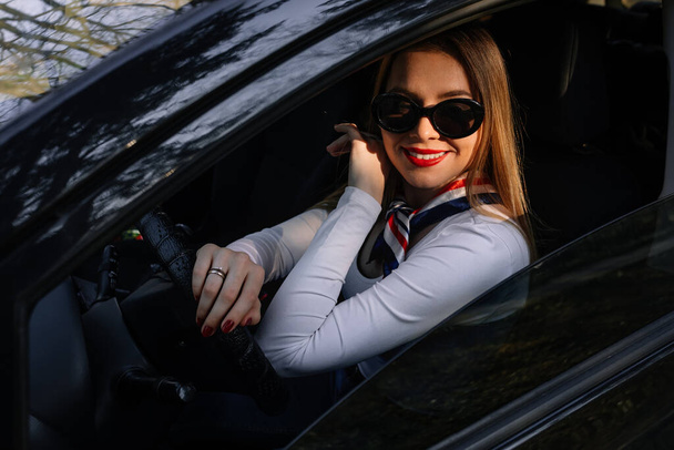 Portrait of beautiful woman in car, looking out of window and smiling.  - Photo, Image
