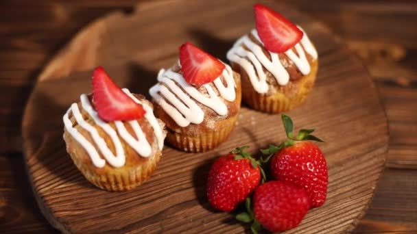 Un délicieux muffin aux fraises se trouve sur une table en bois, et une fraise se trouve à proximité. Le concept d'un délicieux petit déjeuner. Gros plan
. - Séquence, vidéo