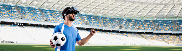 professional soccer player in vr headset with ball yelling and showing yes gesture at stadium, panoramic shot - Photo, Image