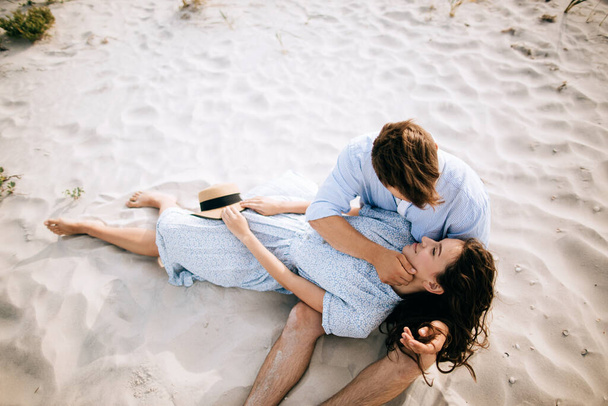 Man and woman lying on the sand on the sea beach hugging and kissing. Summer vacation - Foto, afbeelding
