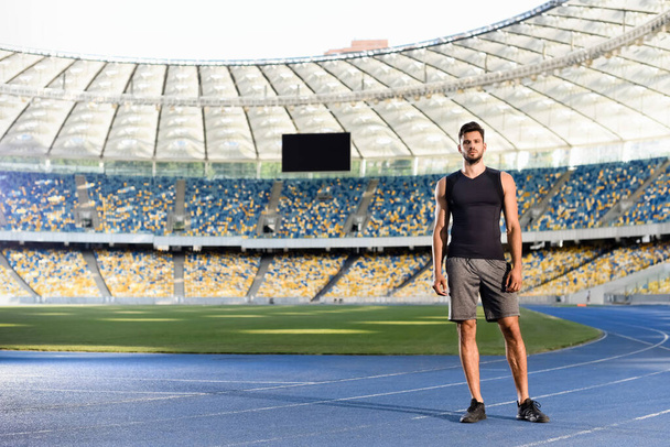 handsome young sportsman on running track at stadium - Foto, afbeelding