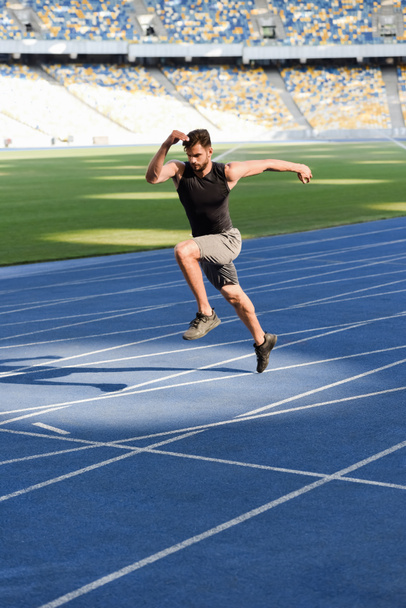 fast handsome runner exercising on running track at stadium - 写真・画像