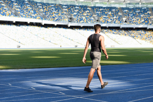 Schöne Läuferin in Startposition auf Laufstrecke im Stadion - Foto, Bild