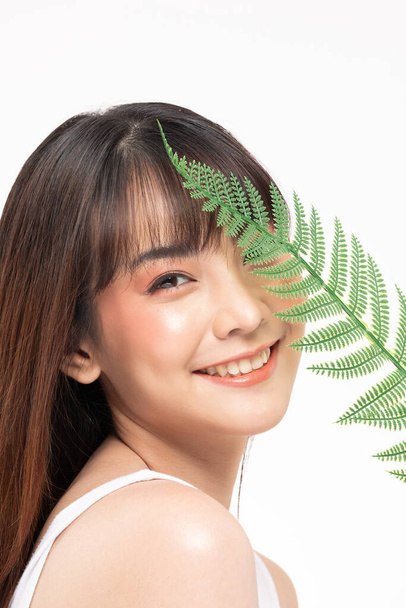 Young Beautiful Asian woman smile with clean and fresh skin with green leaf cover on face,isolated on white background,Beauty Cosmetics and spa Treatment Concept - Foto, afbeelding