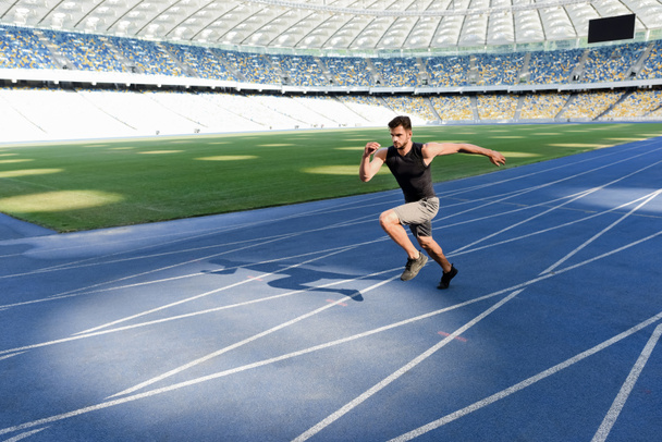 przystojny biegacz ćwiczenia na bieżni na stadionie - Zdjęcie, obraz
