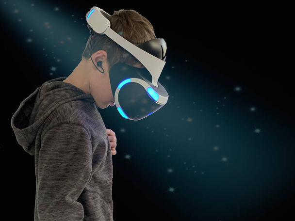 Hombre con casco para realidad virtual, sobre fondo negro. Niño con gafas para ver vídeo en 3D. El chico juega juegos en el mundo virtual. - Foto, Imagen