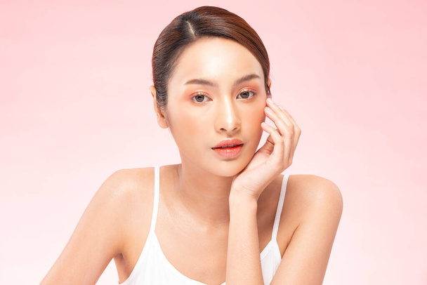 Beautiful Asian woman touching soft cheek smile with clean and fresh skin Happiness and cheerful with positive emotional,isolated on pink background,Beauty Cosmetics and spa Treatment Concept - Photo, Image