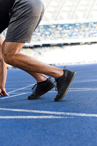 cropped view of runner in start position on running track at stadium - Foto, imagen