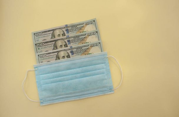 Protective medical mask and dollars on a yellow background. - Fotoğraf, Görsel