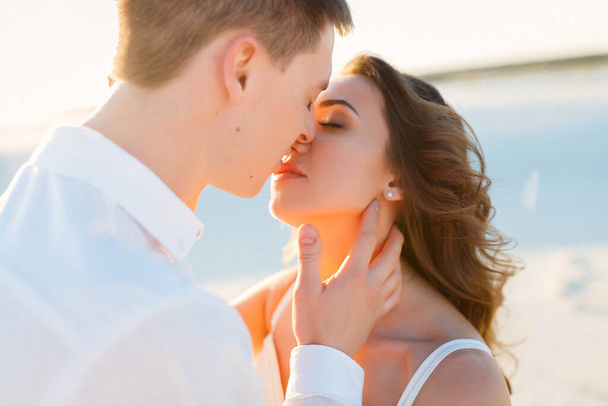 Newlyweds kisses in a white desert during a romantic honeymoon trip. - Zdjęcie, obraz
