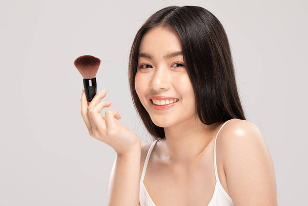 Beautiful Asian young woman smile and holding make up brush with healthy Clean and Fresh skin feeling so happiness and cheerful,Isolated on white background,Beauty Cosmetics Concept - Photo, image