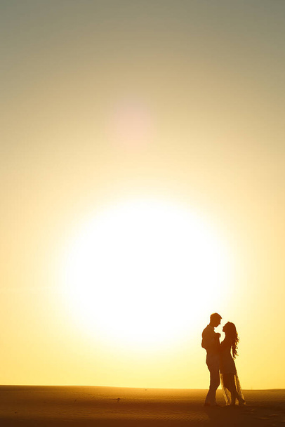 Newlyweds walk barefoot on the sand in the white desert at sunset. - Foto, Imagem