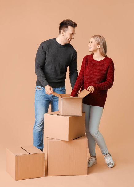Junges Paar packt Dinge auf farbigem Hintergrund aus - Foto, Bild