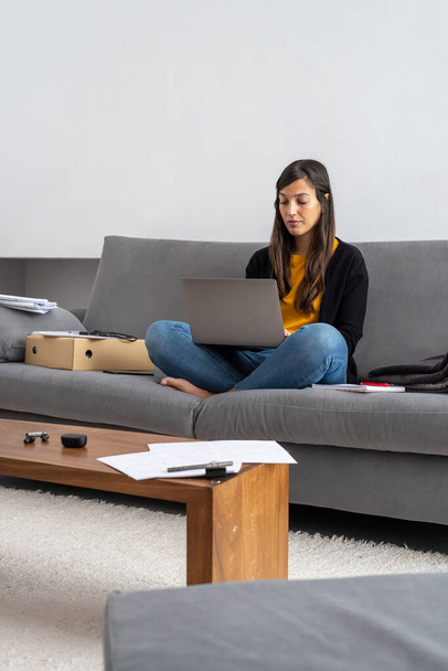Fiatal nő laptoppal távközlés a kanapén az otthonában - Fotó, kép