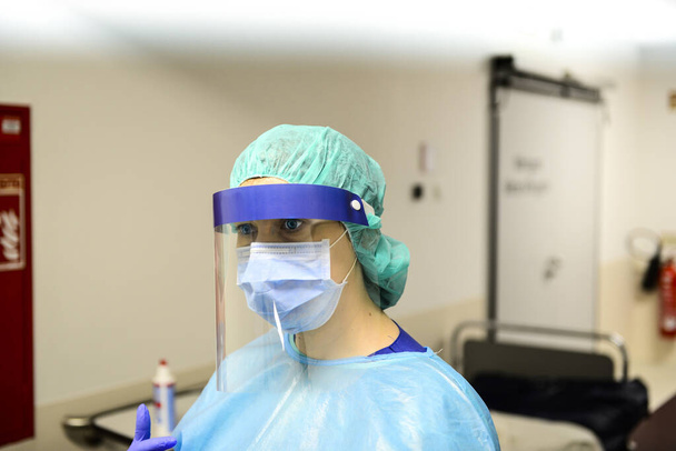 Dokter draagt wegwerpdeken met masker en veiligheidsgoogle in het ziekenhuis. Pandemie 2019 Coronavirus 2019-nCoV. - Foto, afbeelding