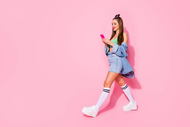 Full size profile photo of pretty lady hold telephone texting friends walk street wear denim jacket green crop top mini shirt long socks shoes isolated pastel pink color background - Valokuva, kuva