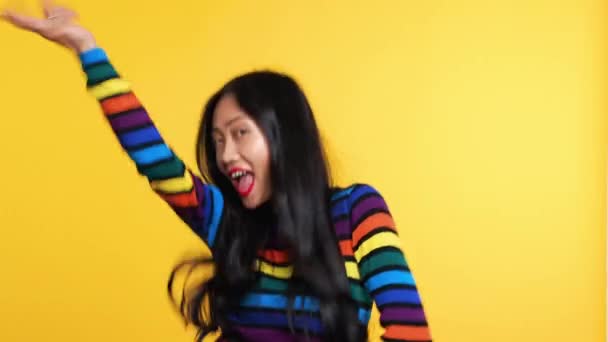 Asian woman funny dancing on yellow background - Кадри, відео