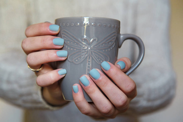 Female hands with manicured fingernails holding grey cup. Health, beauty, hands care concept. - Photo, Image