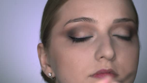 Nahaufnahme einer Visagistin, die junge Frauen im Schönheitsstudio professionell schminkt. Make-up Artist zeichnet Pfeile über Auge, Eyeliner - Filmmaterial, Video