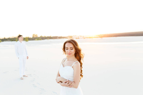 Портрет девушки в белом платье шагает по песку в белой пустыне. - Фото, изображение