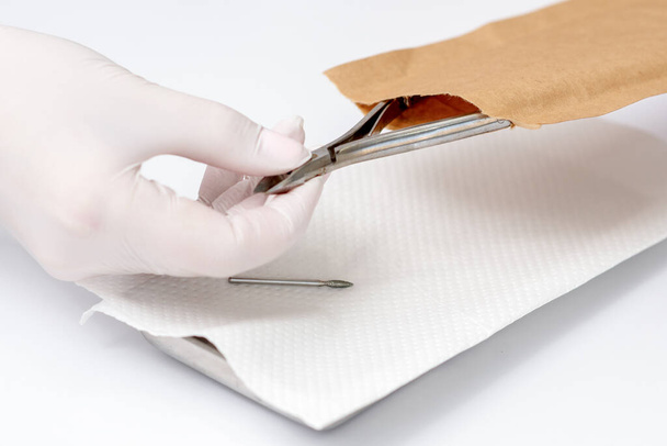 Close-up of manicurist hand is taking manicure tool from craft envelope in manicure salon. - Photo, Image
