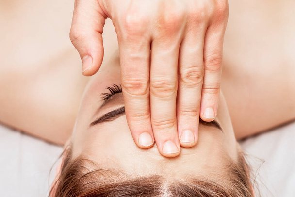 Top view woman receiving forehead massage by fingers of massage therapist. - Фото, зображення