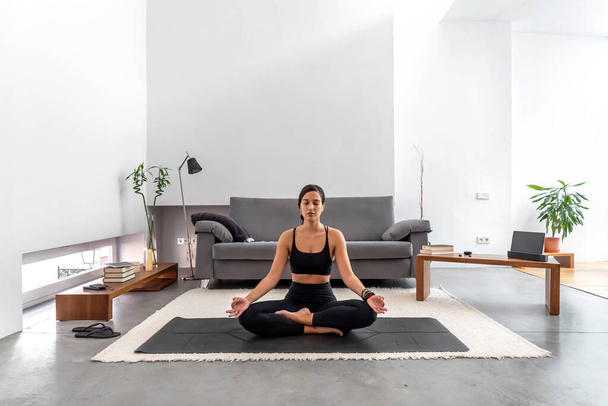 Yoga yapan çekici kadın rahat evinde meditasyona poz veriyor. - Fotoğraf, Görsel