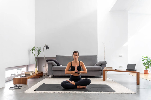 Ελκυστική γυναίκα πρακτική yoga lotus θέτουν σε διαλογισμό στο άνετο σπίτι - Φωτογραφία, εικόνα