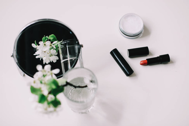 Blossom flowers, cosmetics and a mirror on the dressing table top view. Flat lay with women accessories. Cosmetic composition.   - Foto, Imagem