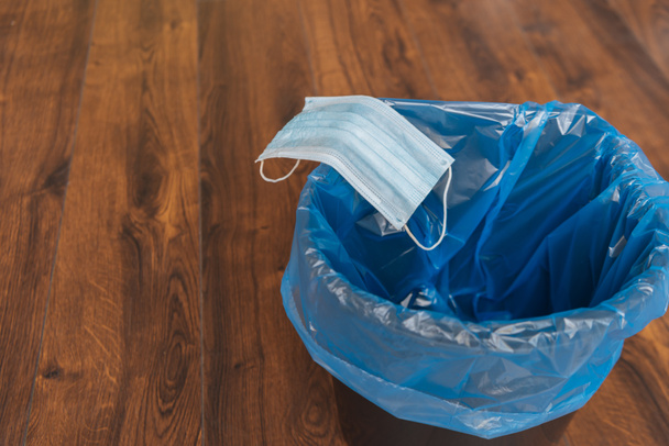 blauw medisch masker in vuilnisbak met vuilniszak, einde quarantaine concept - Foto, afbeelding