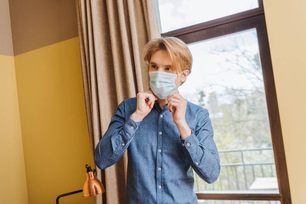 joven tocando máscara médica en casa
  - Foto, imagen