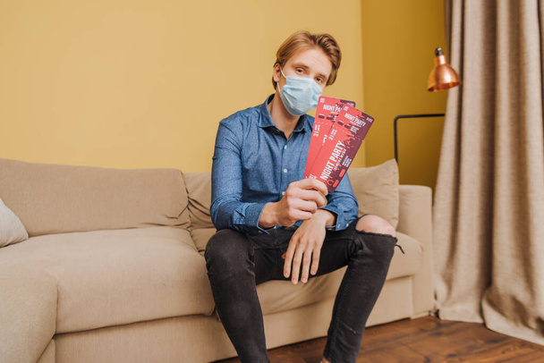 man in medical mask holding night party tickets, end of quarantine concept  - Photo, image