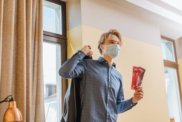 stylish man in medical mask holding night party tickets and jacket, end of quarantine concept  - Photo, Image