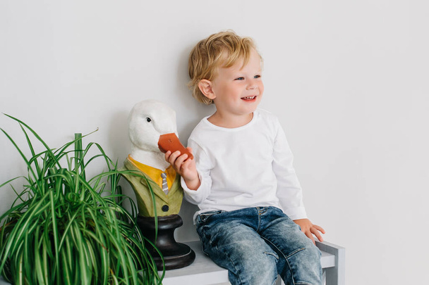 Portrait of a cute boy with a goose bust sitting in the interior - Φωτογραφία, εικόνα