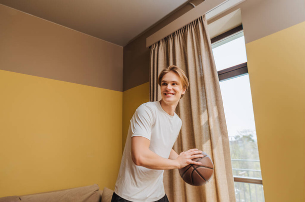hombre sonriente sosteniendo baloncesto en casa, fin del concepto de cuarentena
 - Foto, Imagen