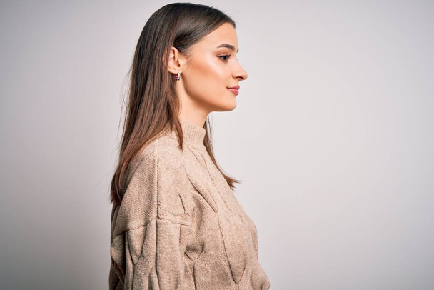 Young beautiful brunette woman wearing casual sweater standing over white background looking to side, relax profile pose with natural face with confident smile. - Φωτογραφία, εικόνα